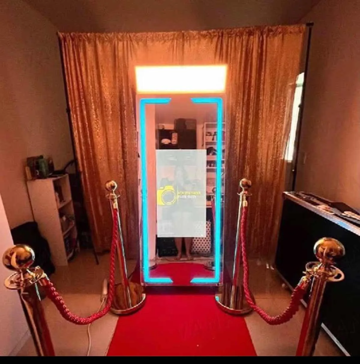 Cabina de fotos montada con cortinas rojas, alfombra roja y postes dorados