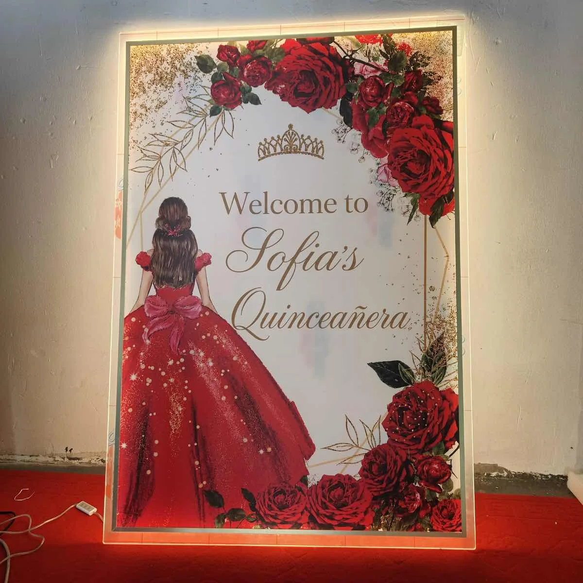 Letrero iluminado de bienvenida para una quinceañera, con rosas rojas y detalles dorados